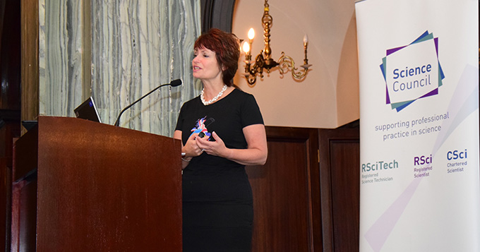 Professor Dame Anne Glover stands at a podium delivering a lecture