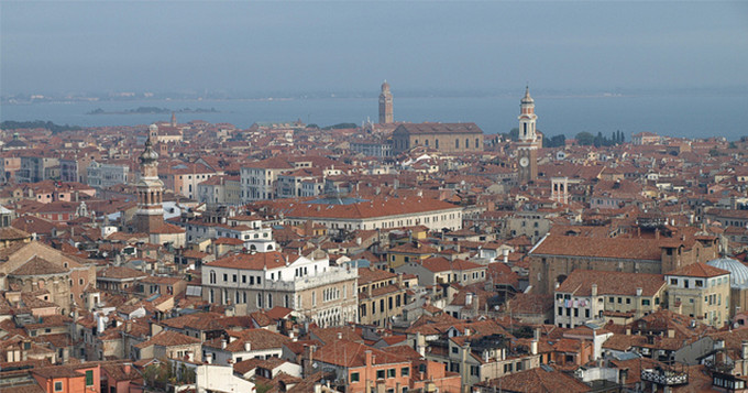 Birds-eye photo of a city with the sea in the distance