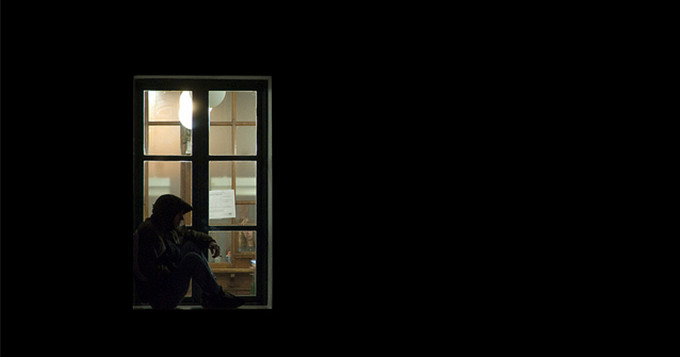 Man sitting on the ledge of a window at night