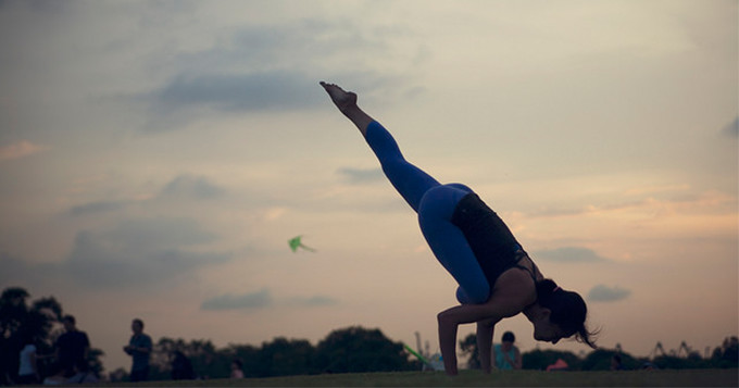 Woman doing yoga in the park at sunset