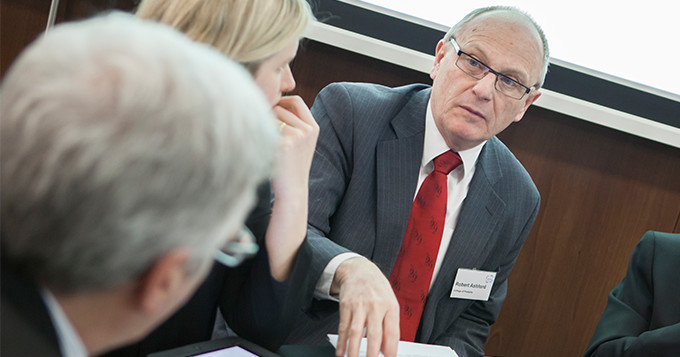 Group of people sitting around a round table at a meeting having a discussion