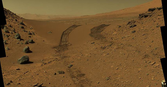 Vehicle tracks on yellow soil on surface of Mars