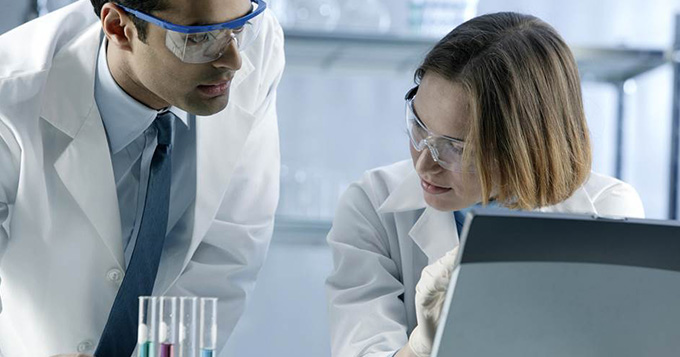 Investigator scientists in a lab discussing results at a computer