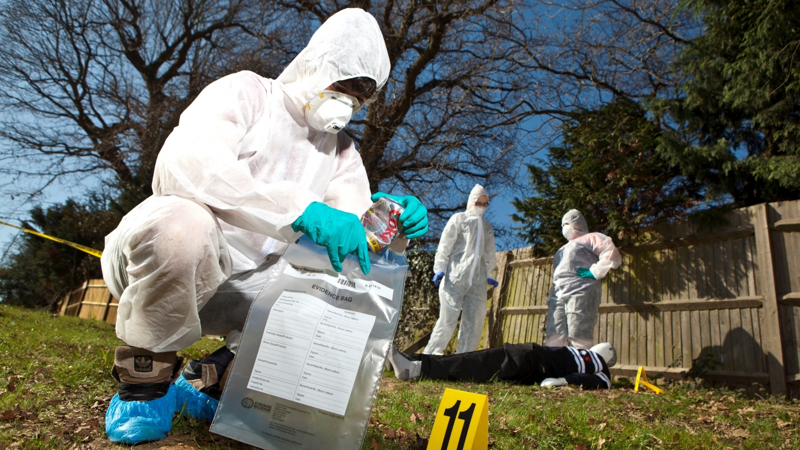 Forensic science students in white overalls examining a mock crime scene - demonstrating work experience