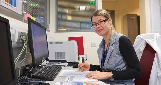 Affinity Water scientist sits in the office working at a computer and reading reports