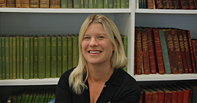 Dr Bev Mackenzie (Science Council trustee) sits with a smile in front of shelves of books