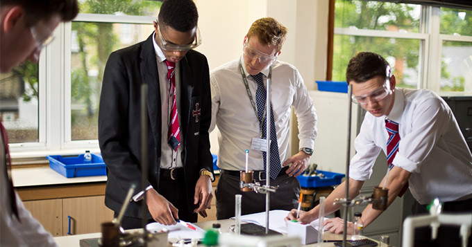 School and college students doing a science practical while being supervised by a teacher