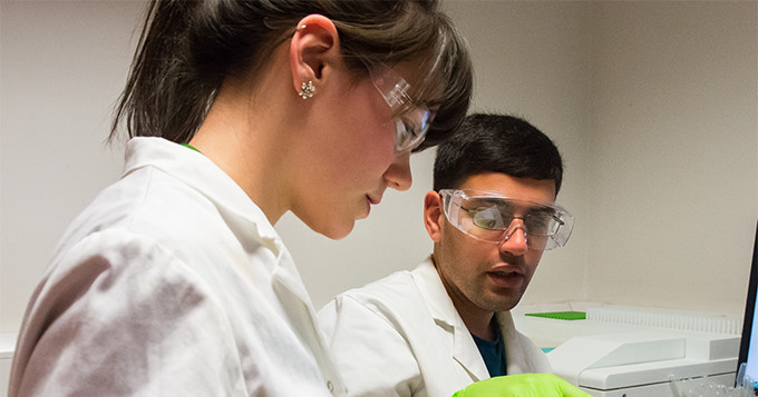 Science students in lab coats and safety glasses