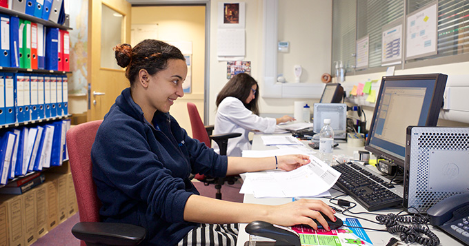 Young girl with bun sits at computer smiling