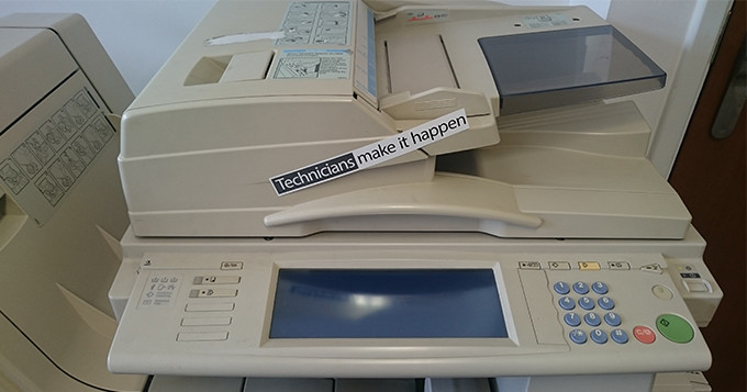 Office printer with 'Technicians Make it Happen' sticker