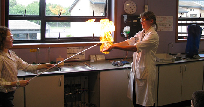 Science technician Stacey RSciTech stands in a classroom demonstrating a science experiment