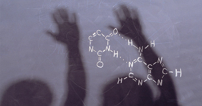 Blackboard with molecular equation written and a shadow of children's raised hands