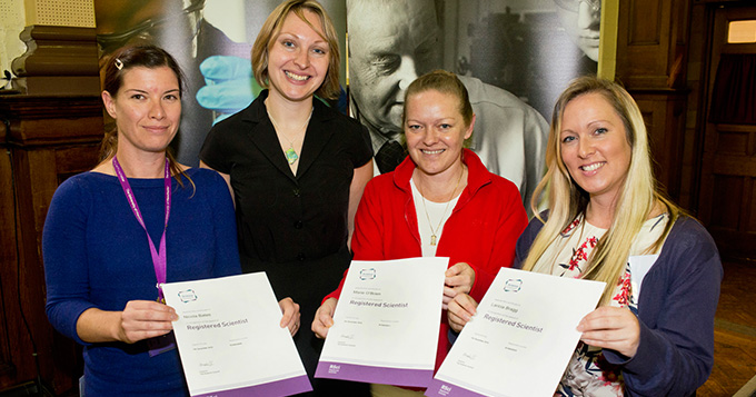 Four women standing together, 3 holding certificates that say Registered Scientist