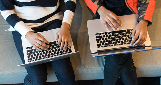 Two women working on laptops by Women of Color in Tech