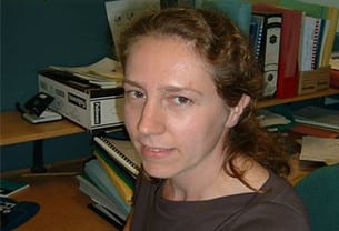 Katharine, Chartered Scientist, sits at an office desk with files and folders on her desk