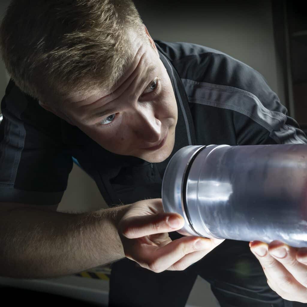 Man in a dark room inserting an opaque tube into a machine