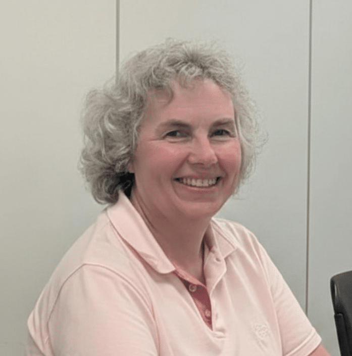 Dr Jeffreys smiles to the camera against a white background. She is wearing a light pink polo shirt.